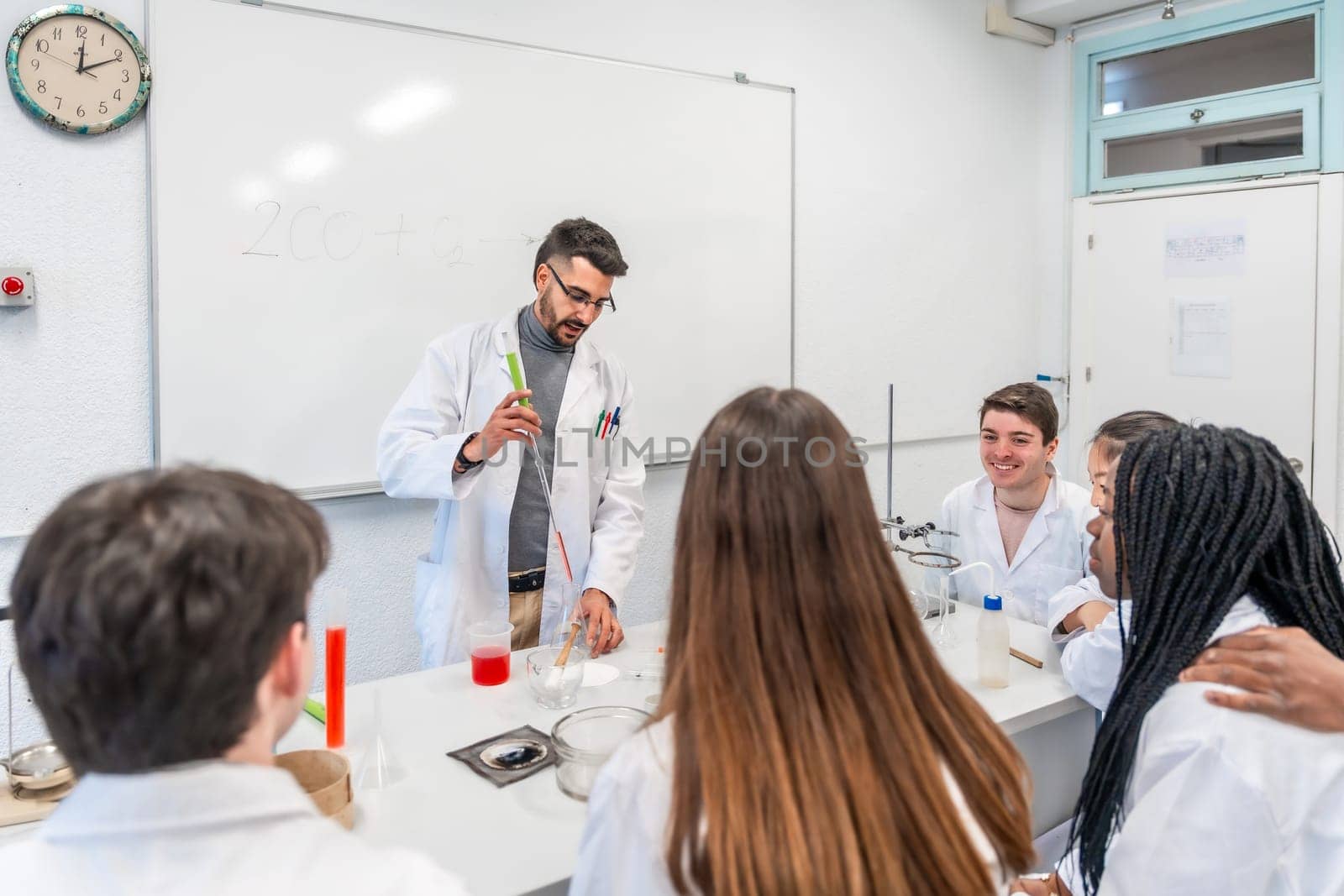 Chemistry teacher performing a titration experiment for a multi ethnic group of students in a university laboratory
