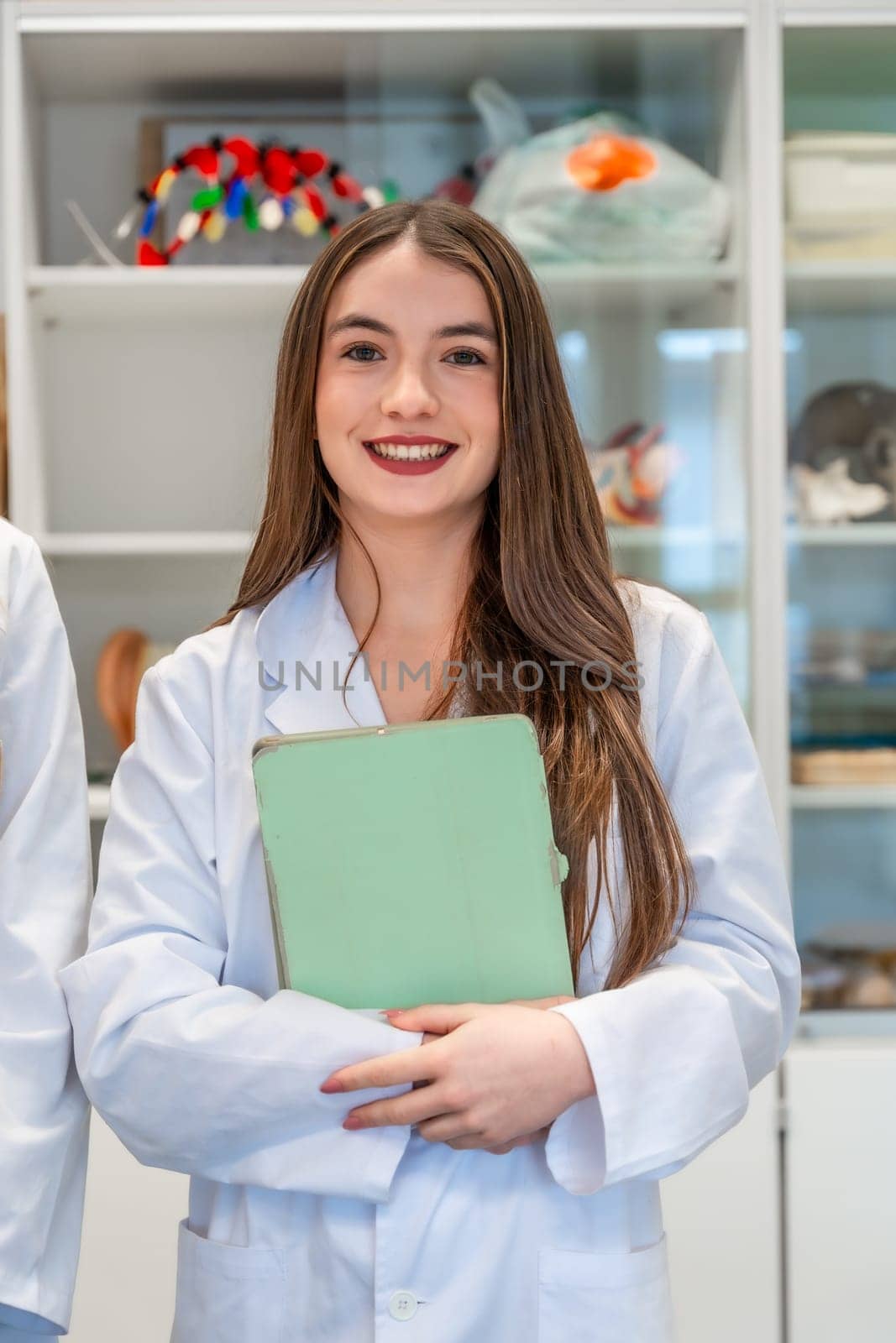 Portrait of a smiling medical student holding a folder in a university laboratory, showcasing her dedication to healthcare education