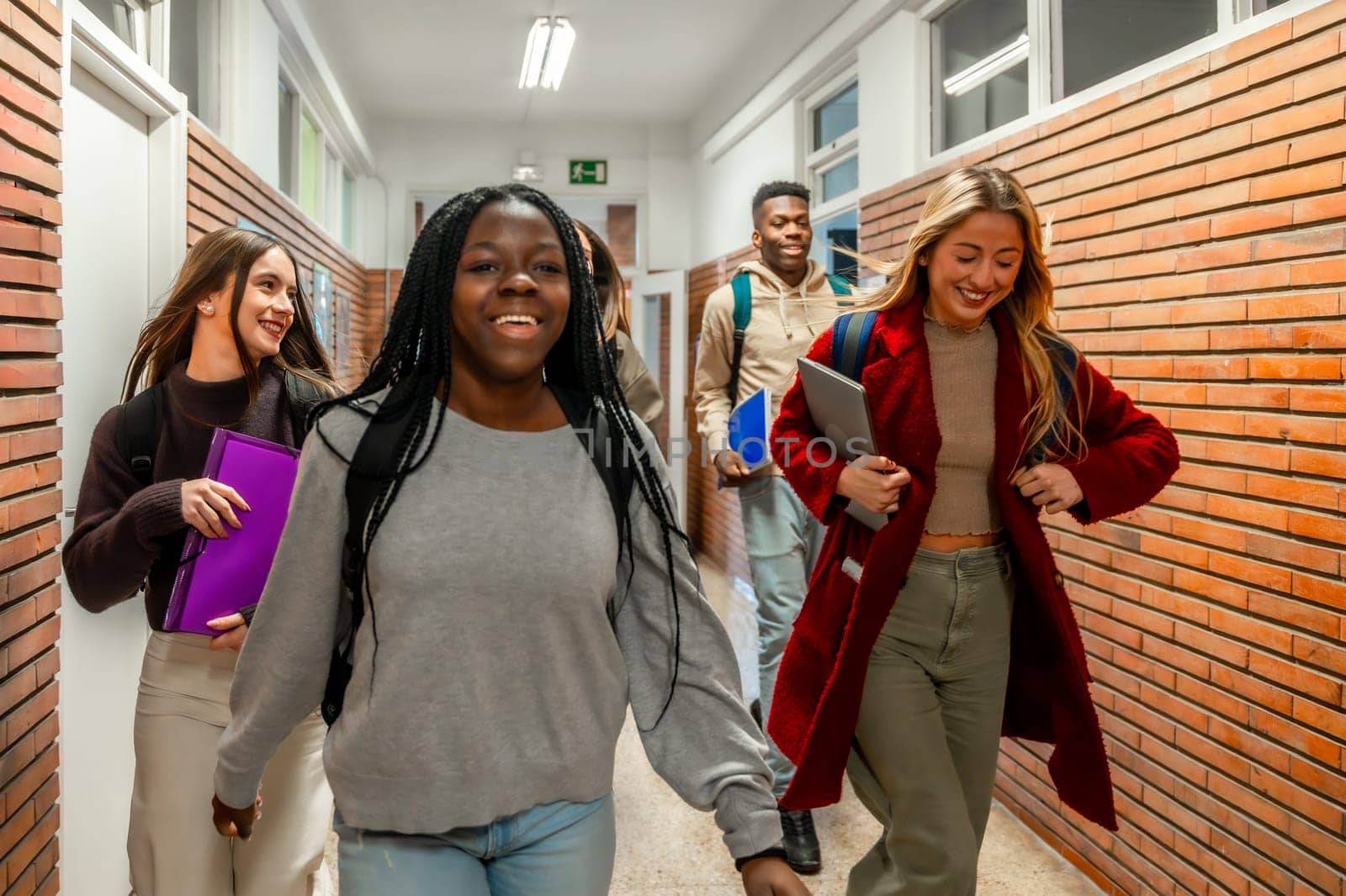 Cheerful multi ethnic university students walking together in a bustling school corridor, sharing laughter and enjoying their college experience