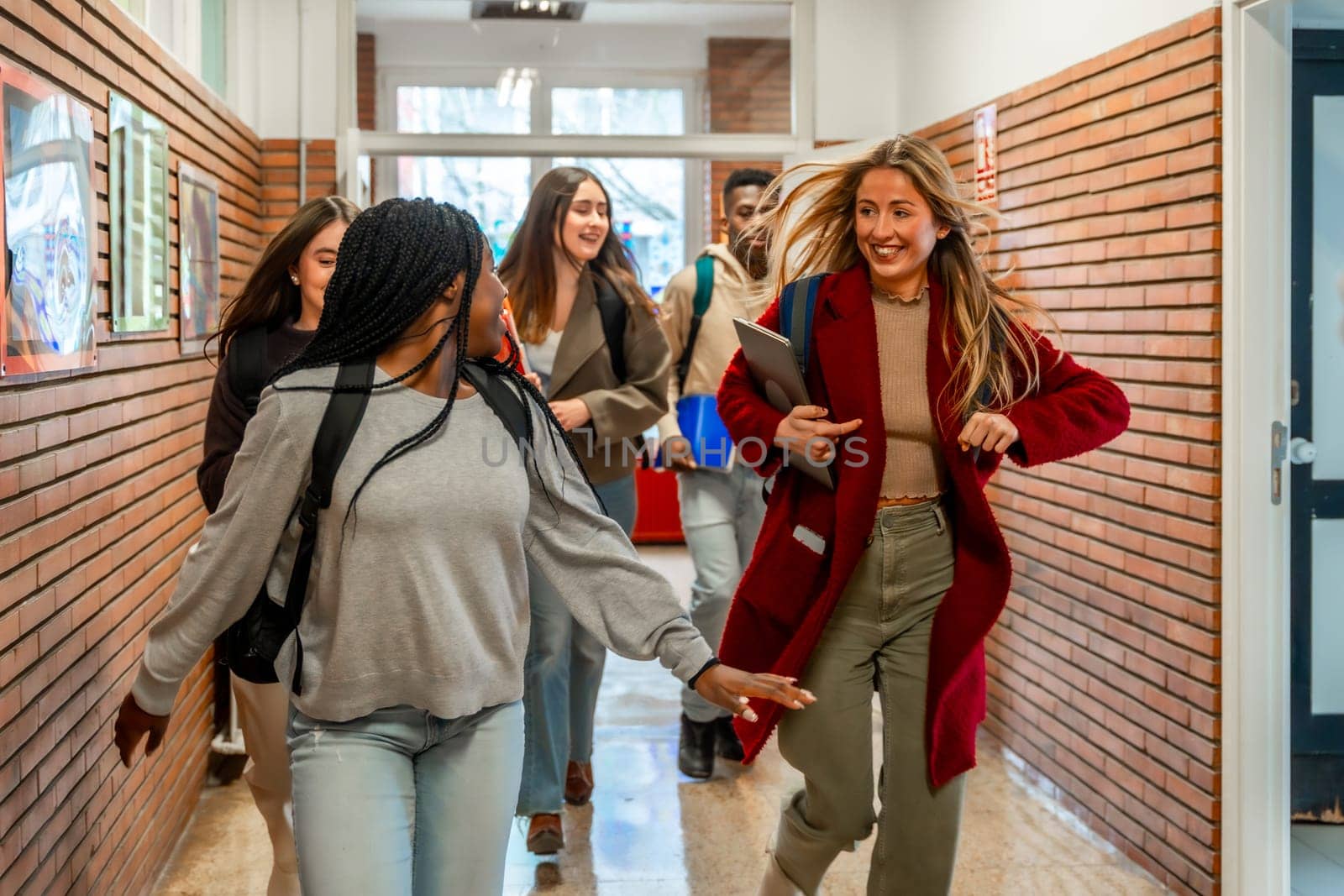Cheerful diverse university students running joyfully through the school hallway after class, filled with energy and excitement for break time