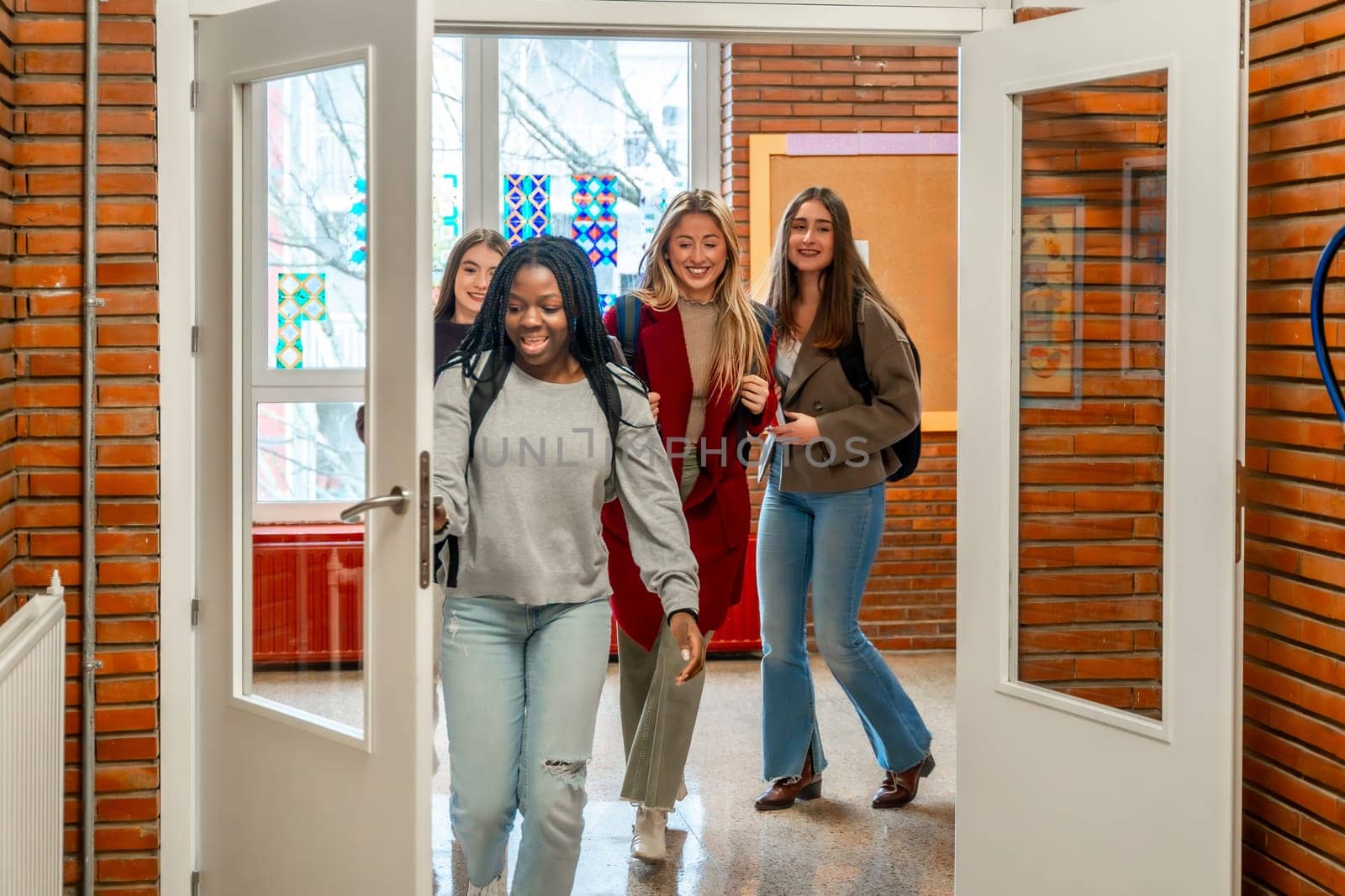 Cheerful female students are walking out of the classroom after their lesson at the university
