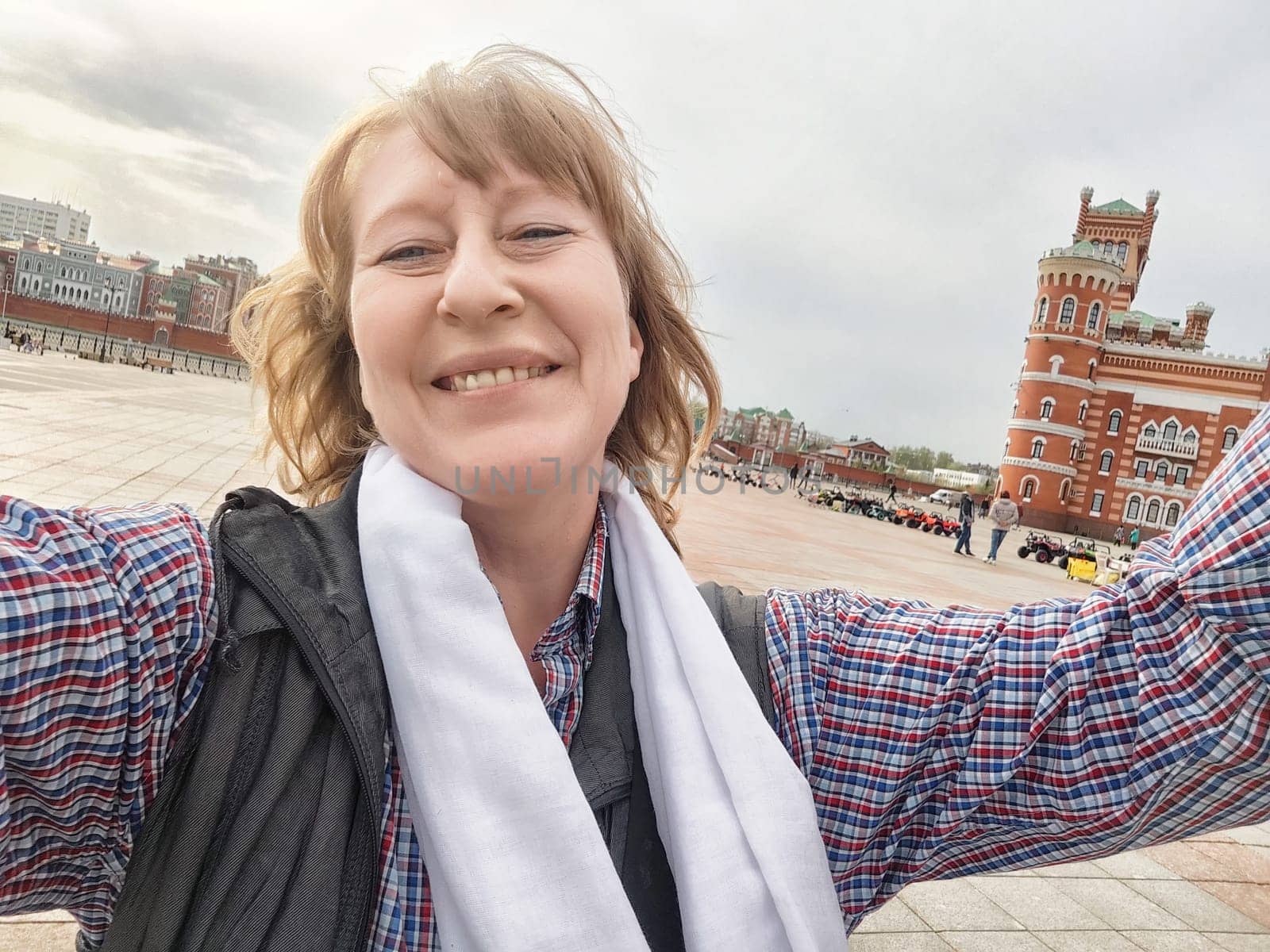 A joyful middle-aged woman captures her adventure in front of a beautiful historic structure while traveling.