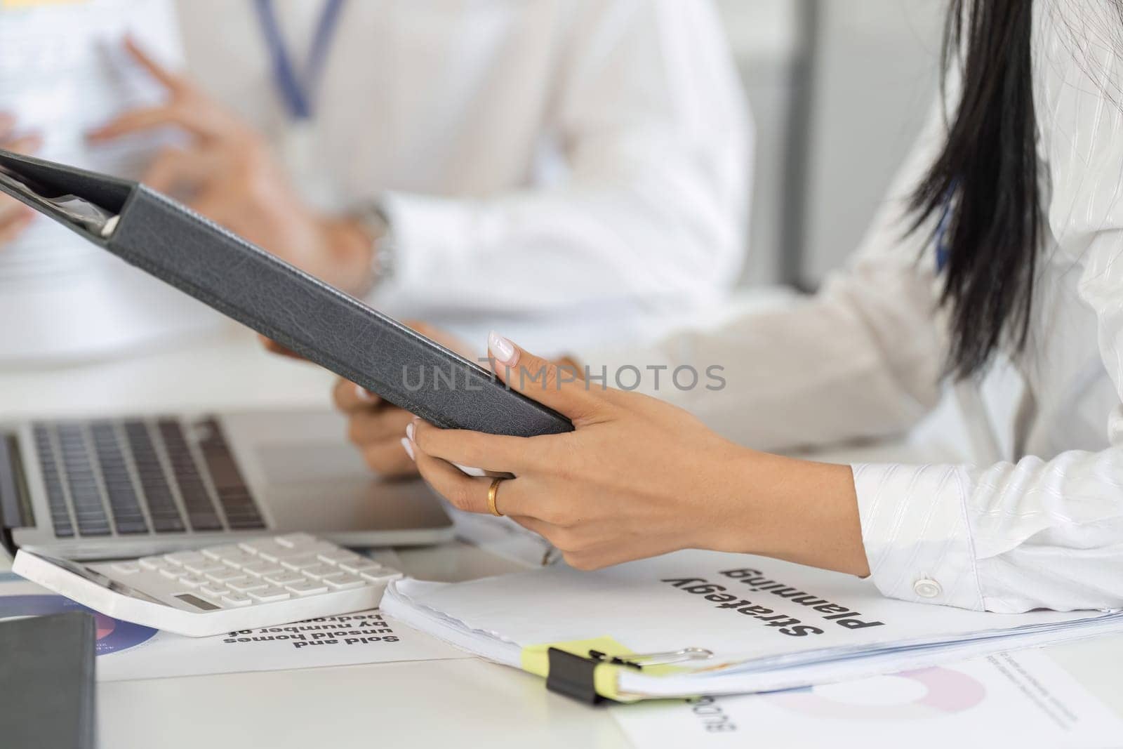 A financial advisor presents strategic planning documents to a client, facilitating a comprehensive discussion on financial management.