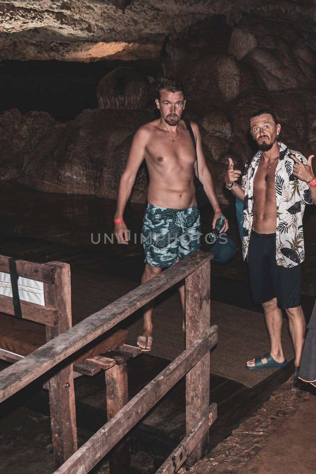 Mean male tourists friends are posing and climbing in the turquoise green blue water and rocks in cenote Yaxmulito in Tulum Quintana Roo Mexico.