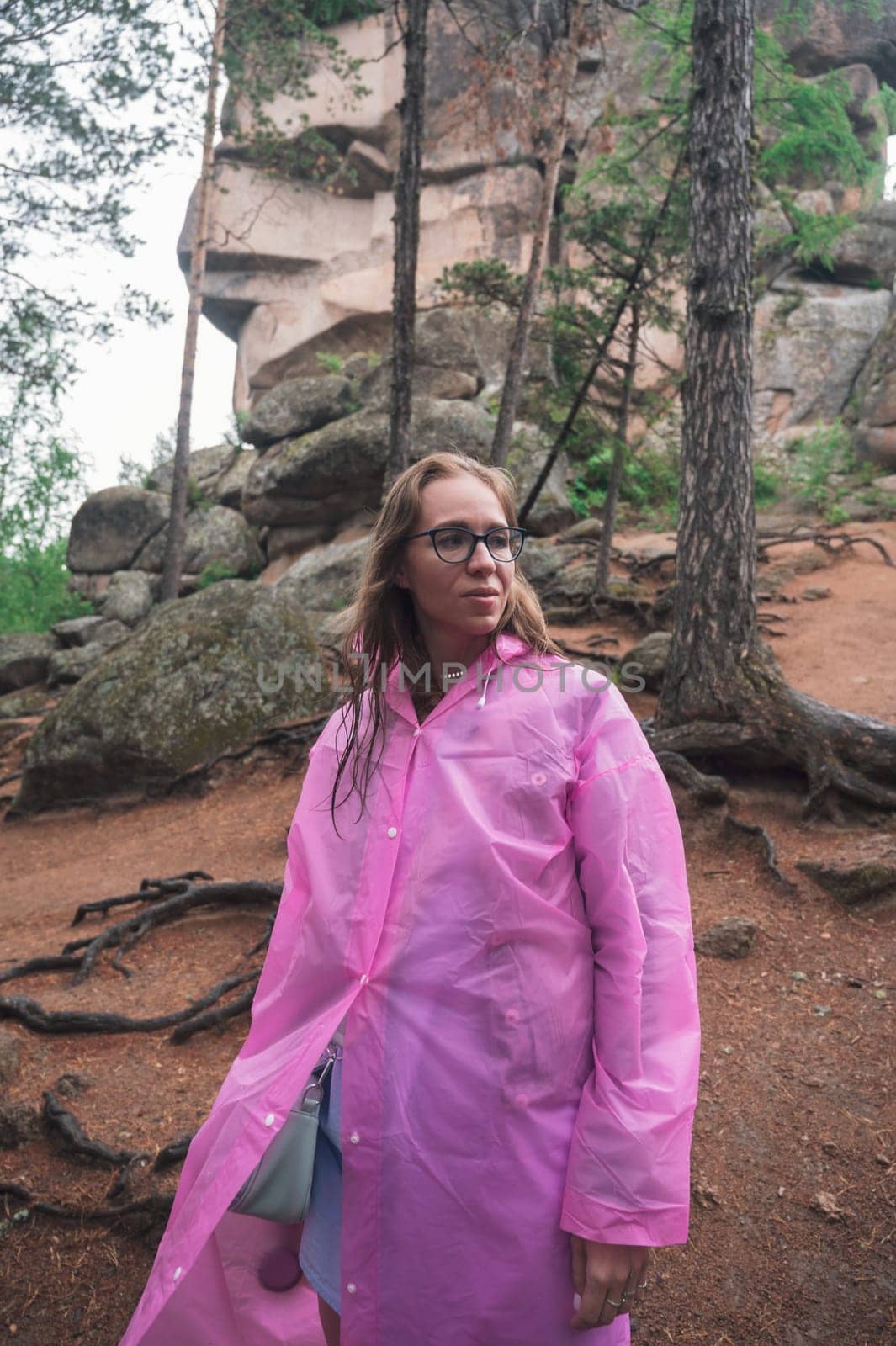 Woman in raincoat in the taiga forest and rocks of the Stolby nature reserve park, Krasnoyarsk, Russia