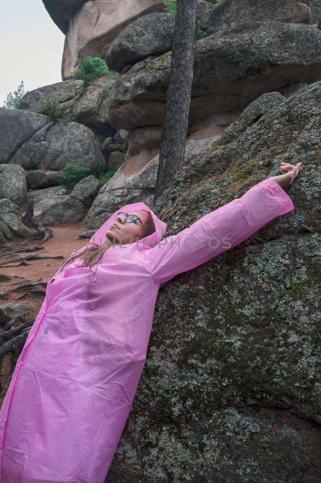 Portrait of woman in the raincoat the taiga forest and rocks of the Stolby nature reserve park, Krasnoyarsk, Russia