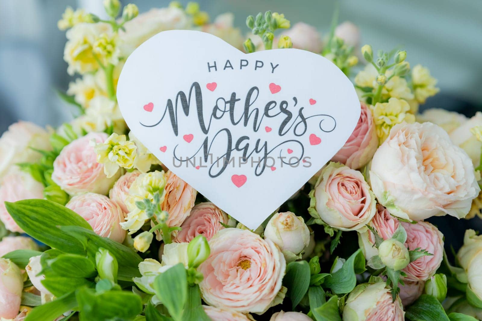 Amazing tender bouquet with pink ranunculus, violet Alstroemeria flowers and tiny white roses in cardboard box with pink ribbon. Beautiful bunch of spring flowers. Easter gift. Seasonal spring flowers