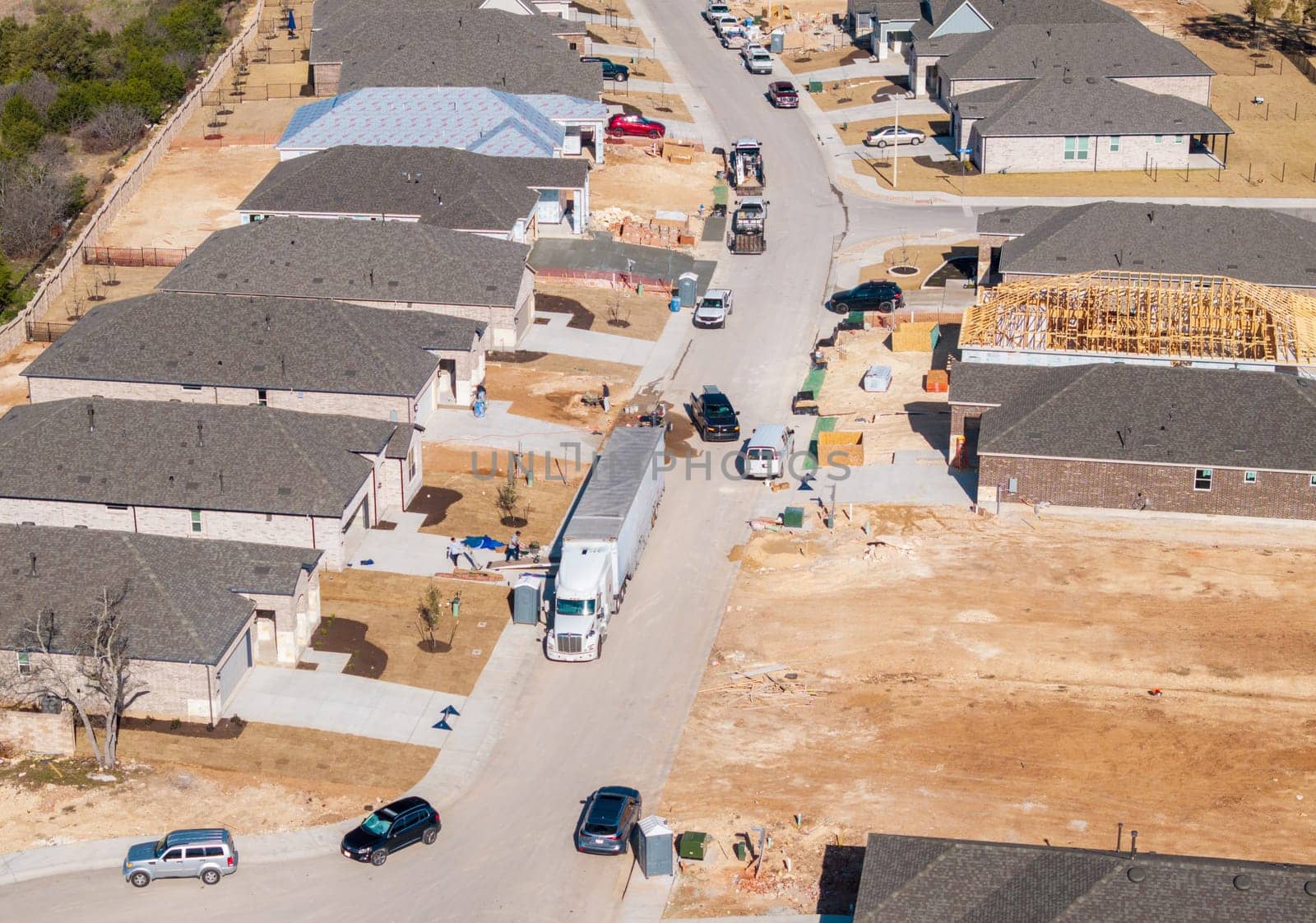 Aerial view of a moving truck unloading boxes in a new suburban neighborhood in Georgetown, Texas, during a sunny day.
