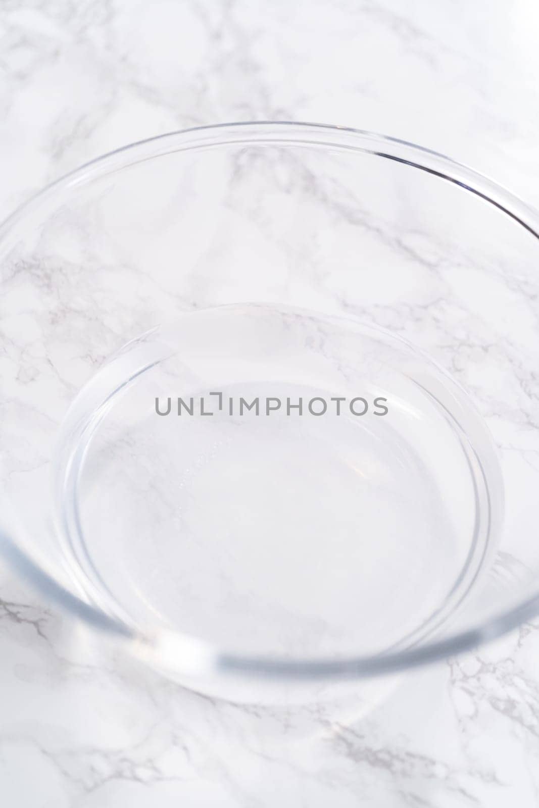 A spacious glass mixing bowl filled with water sits prepared to gently cleanse a batch of ripe strawberries, ensuring they are pristine before drying or storage.