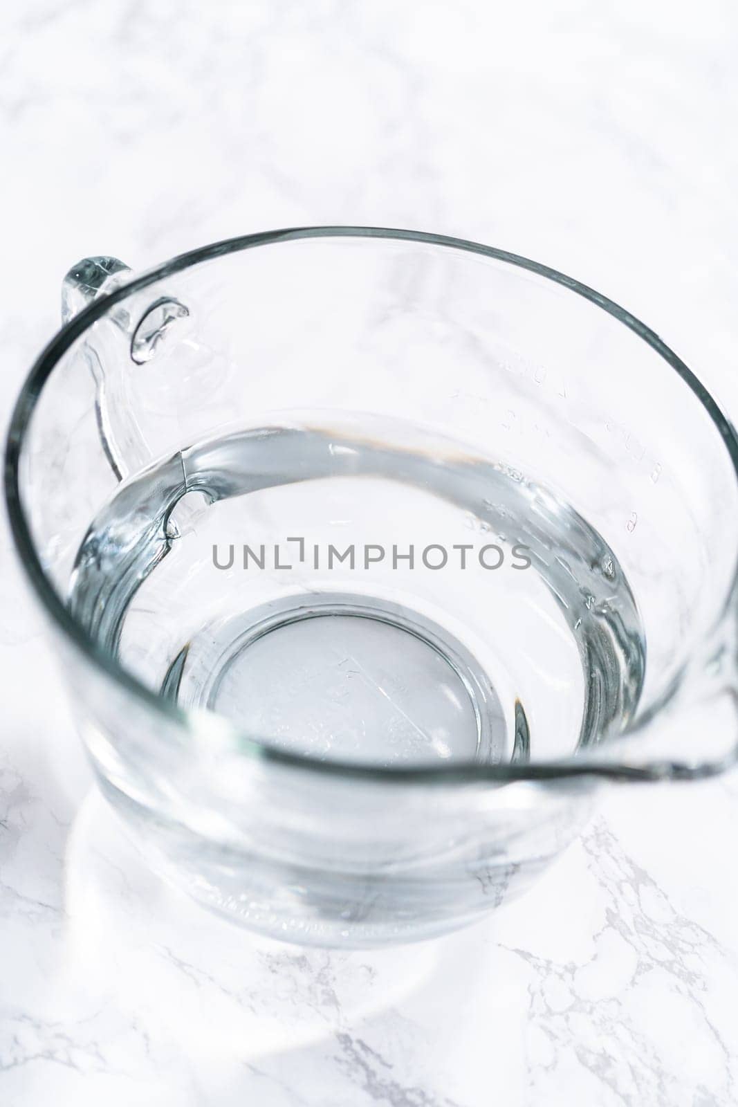 Glass measuring cups are filled with water, lined up and ready to be used in the careful washing of fresh strawberries, ensuring precise and thorough cleaning.