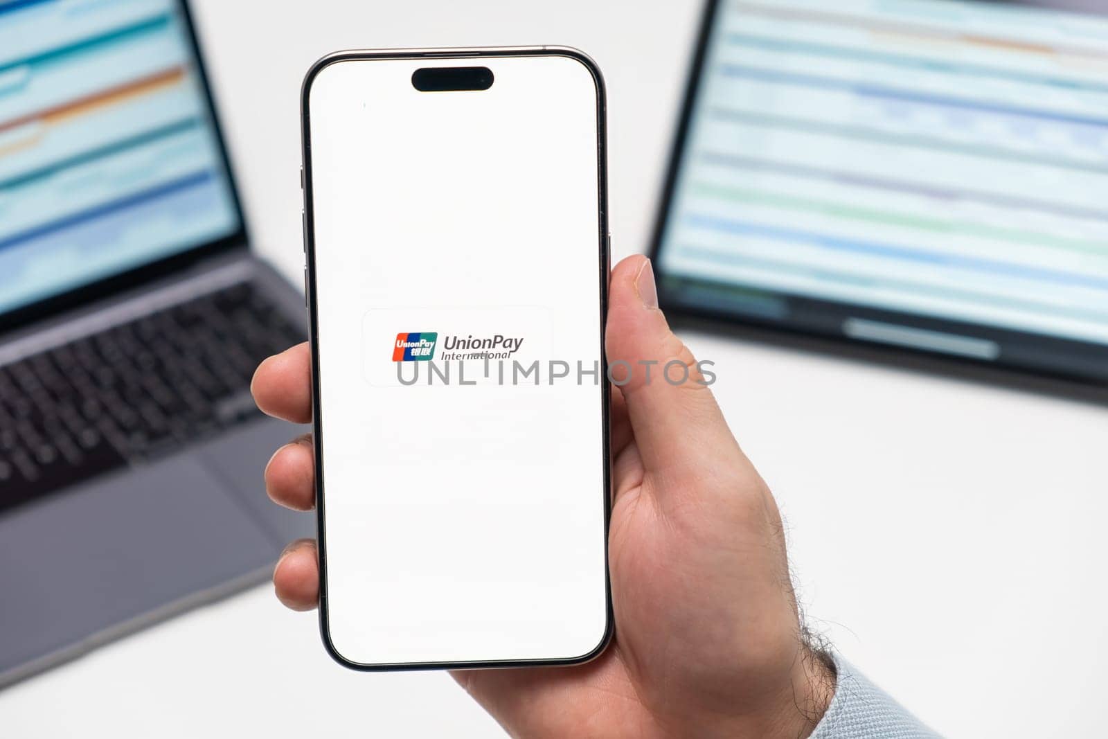 PRAGUE, CZECH REPUBLIC - JANUARY 21 2024: Union Pay logo on the screen of smartphone in mans hand on the workplace background.