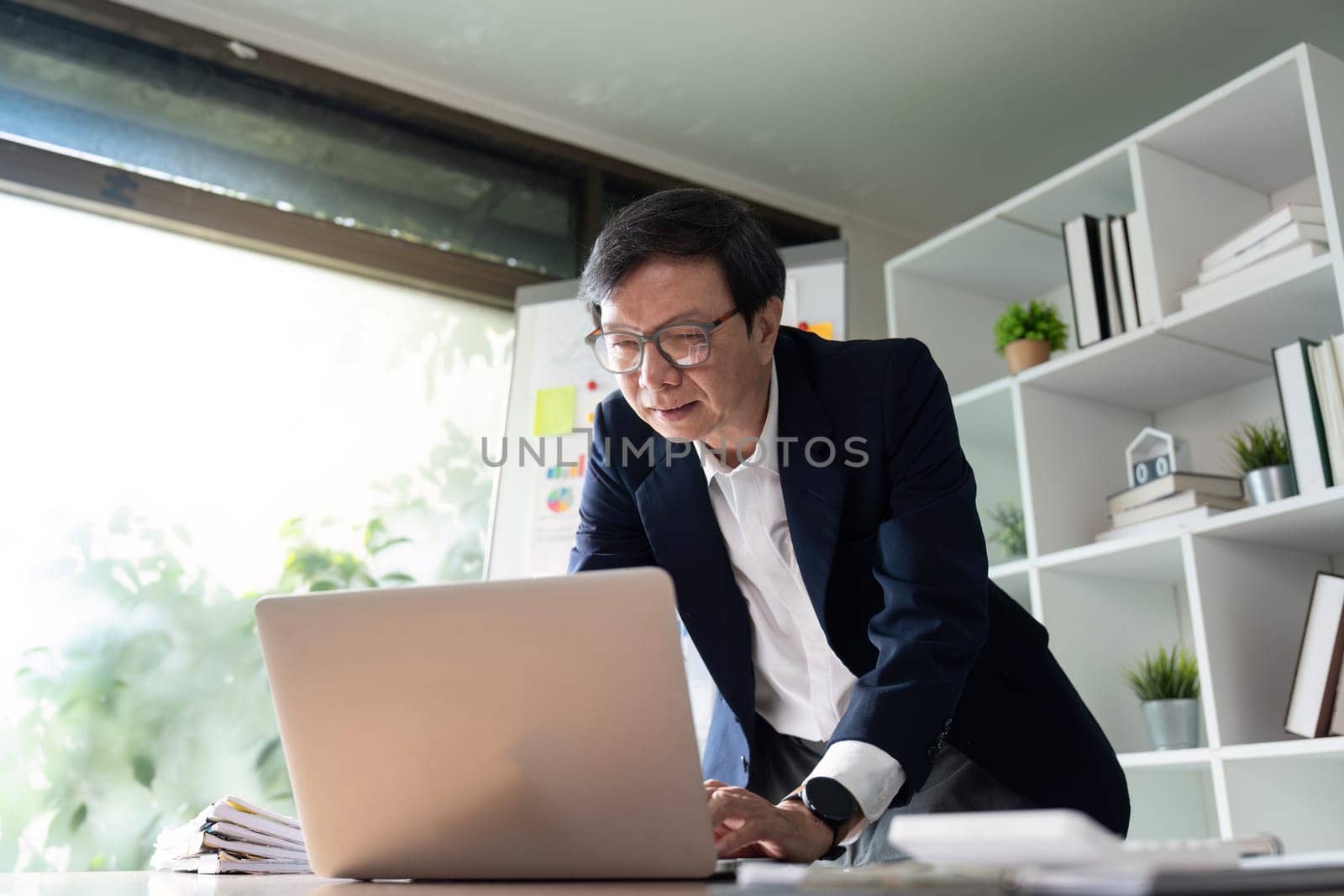 An elderly financial analyst presents insights from budget charts in a modern office, focusing on strategic financial planning and analysis.