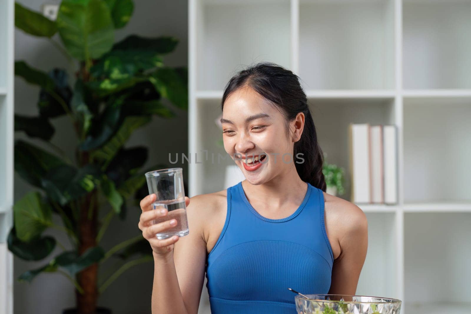A smiling woman holds a glass of water, emphasizing the importance of hydration in a healthy lifestyle.