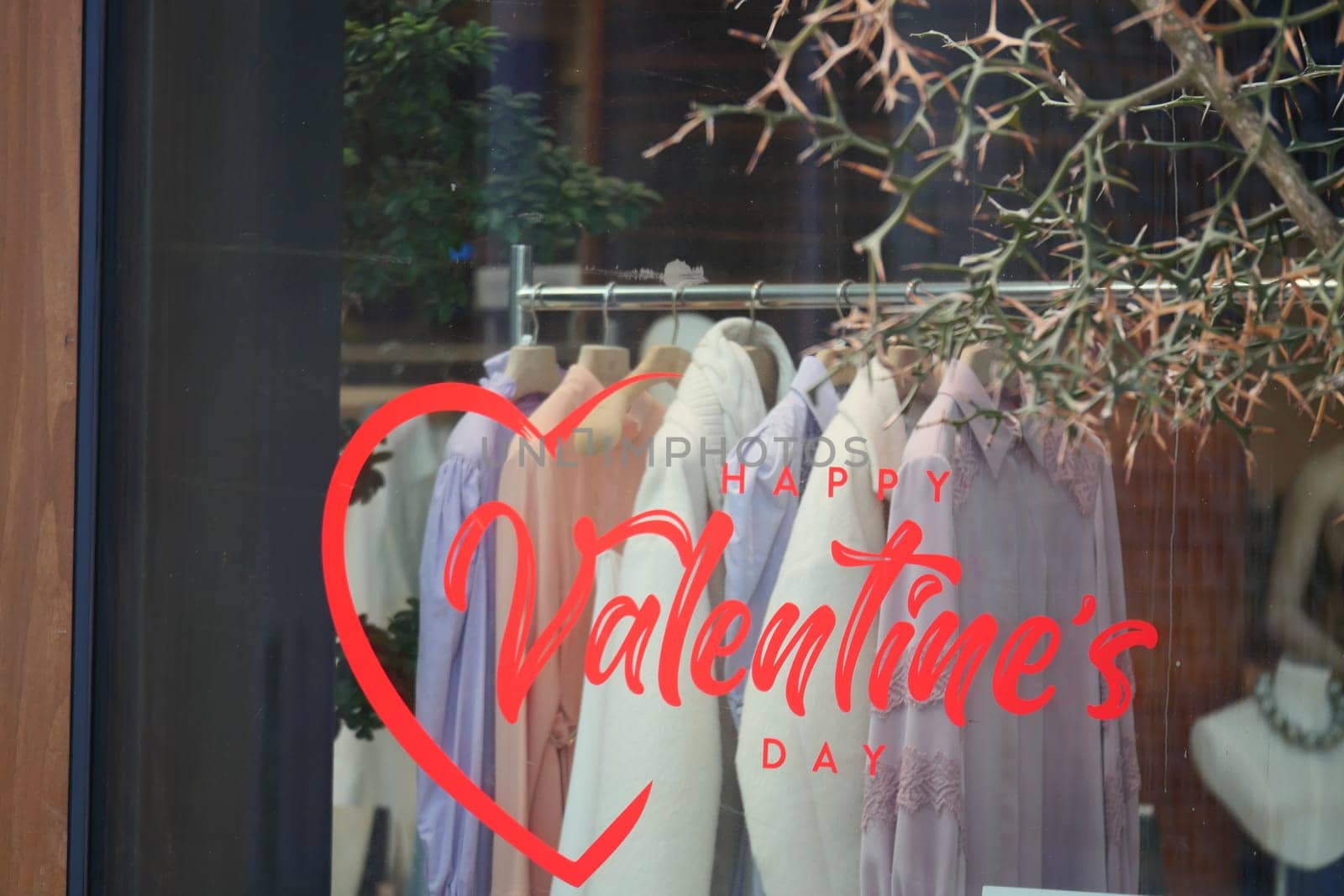 Store window featuring Valentine's Day decorations and stylish clothes.