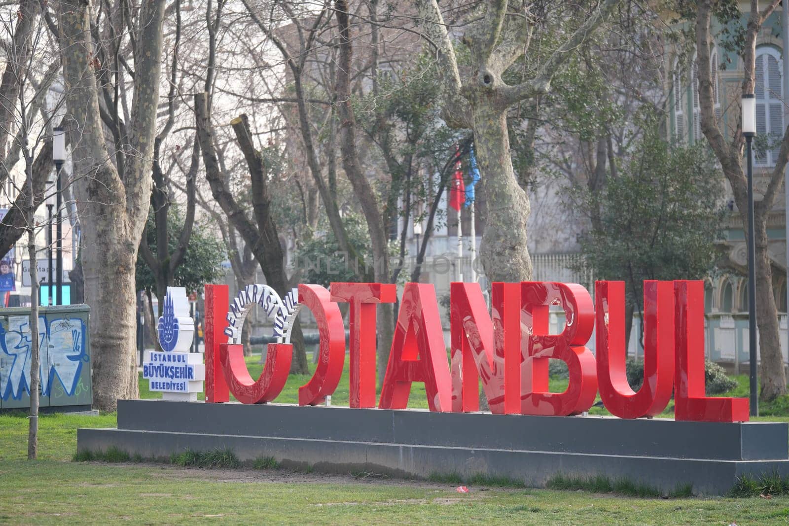 Bold red sign spelling Istanbul stands prominently in park setting.