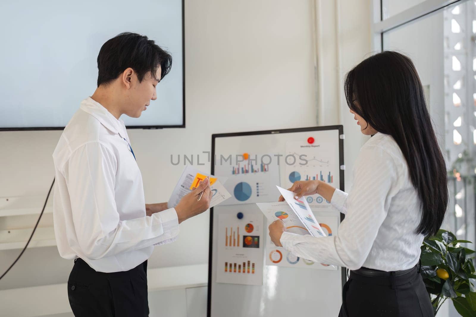 A male and female professional review financial reports and tax data together, fostering collaboration in a workspace.