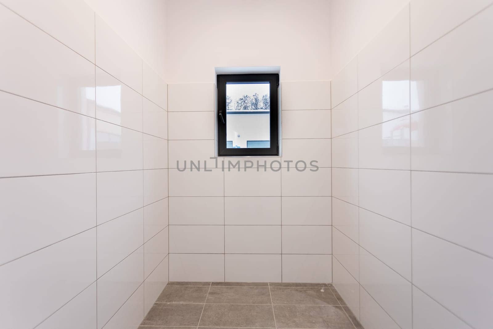 This clean, minimalist room with tiled walls and a large window suits contemporary design aesthetics well