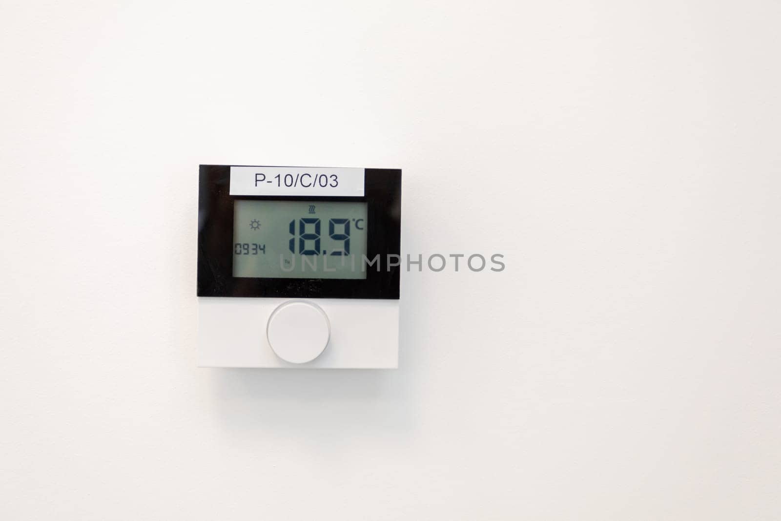 A sleek thermostat showing a temperature of 18.9C on a plain white wall