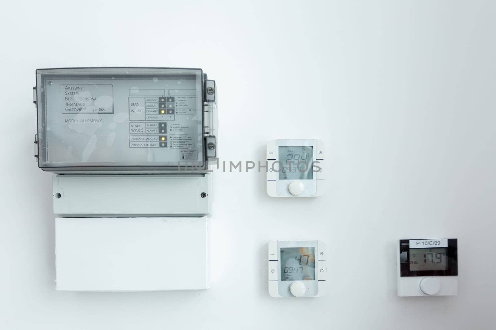A modern electrical panel along with thermostats is securely mounted on a beautifully clean, minimalist wall