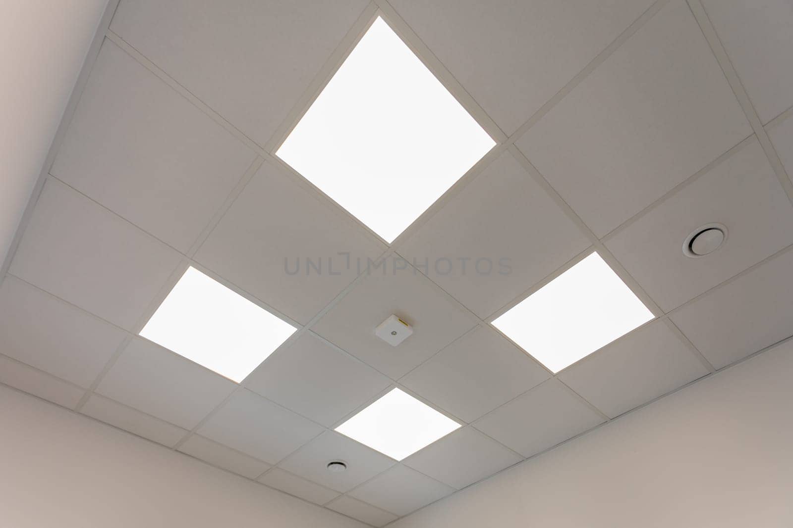 A bright and modern office ceiling design that prominently features advanced LED panel lighting for efficiency