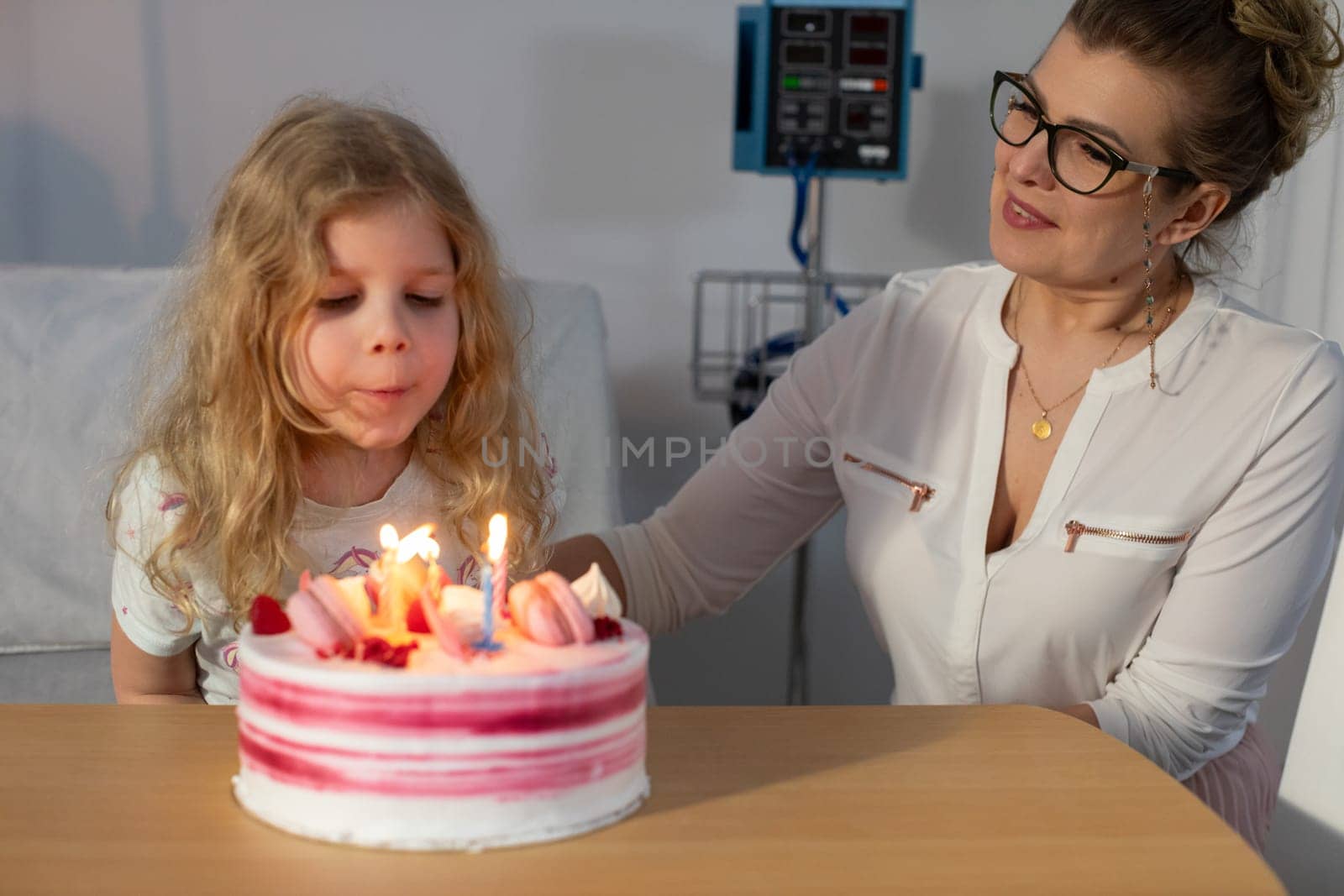 A young girl joyfully celebrates her special birthday with a delicious cake while being in a hospital setting