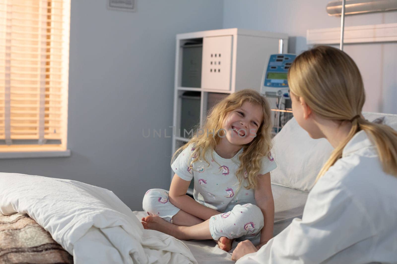 A dedicated nurse interacts warmly with a young girl in a hospital environment, showcasing deep compassion and care
