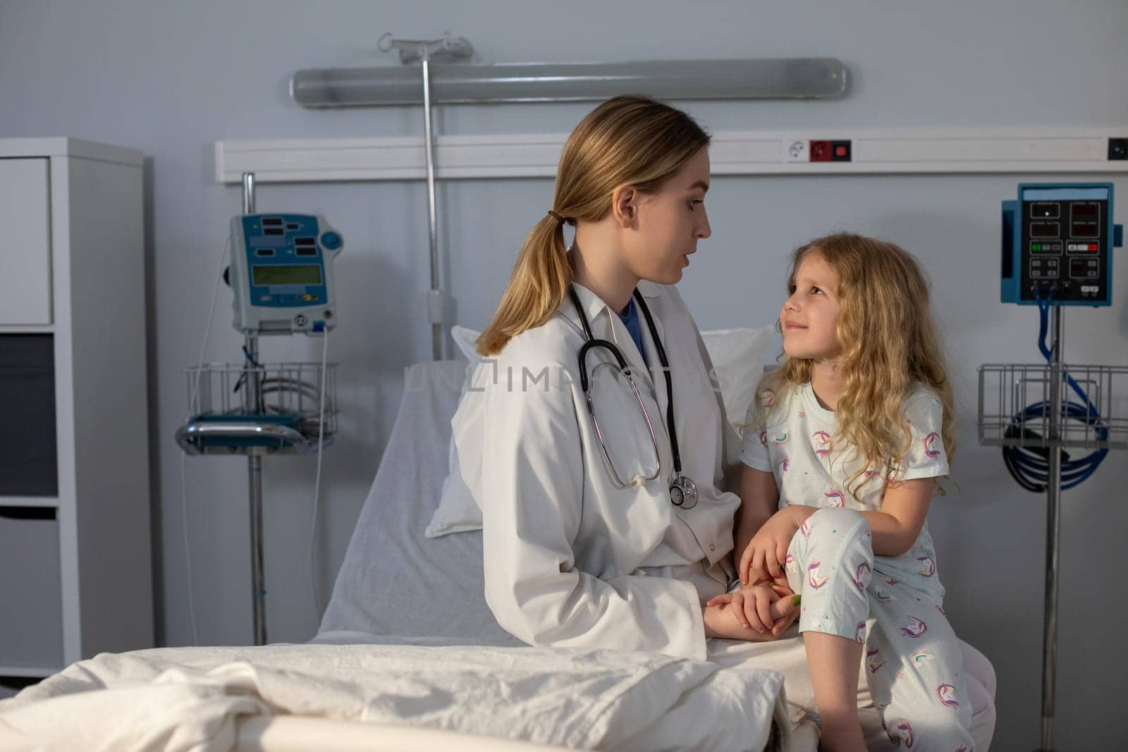 In a clean hospital setting, a nurse interacts warmly and compassionately with a young patient, providing care