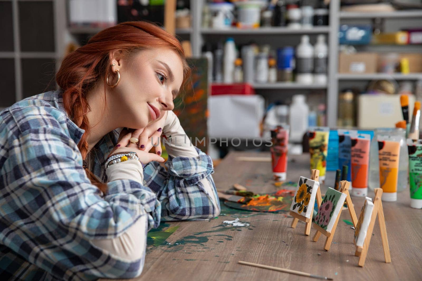 An introspective artist surrounded by vibrant paints and a blank canvas, inspired by their creativity