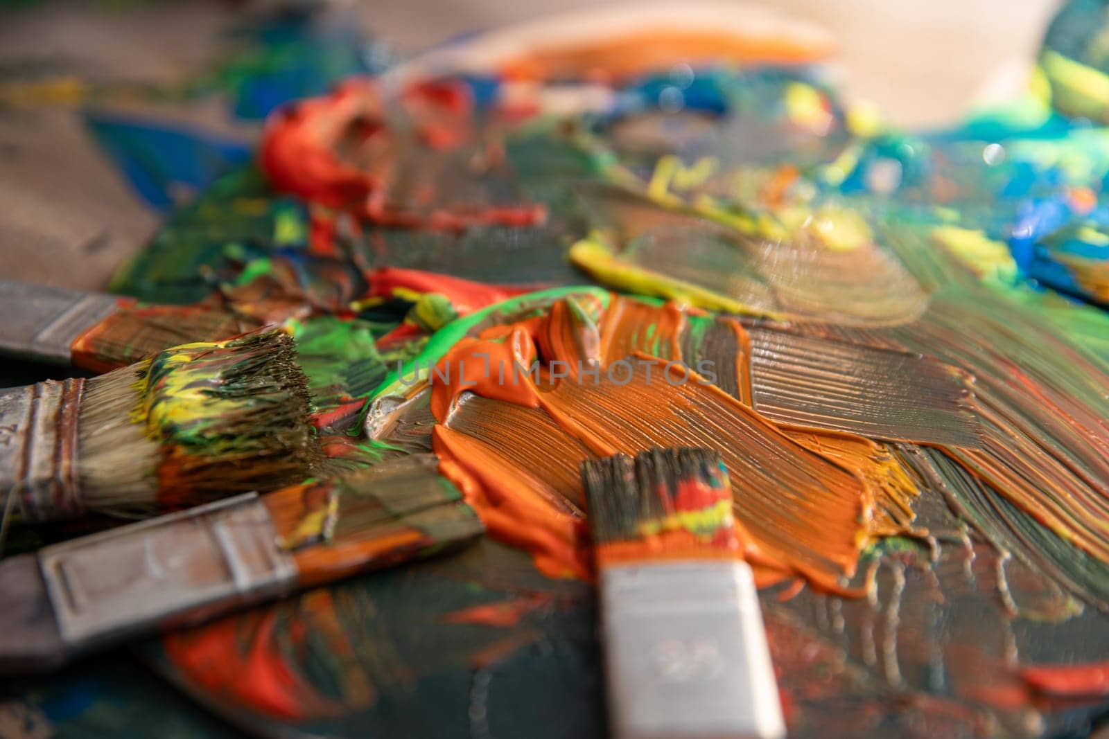 A closeup view of a vibrant and colorful paint palette accompanied by brushes, illustrating vivid artistic expression