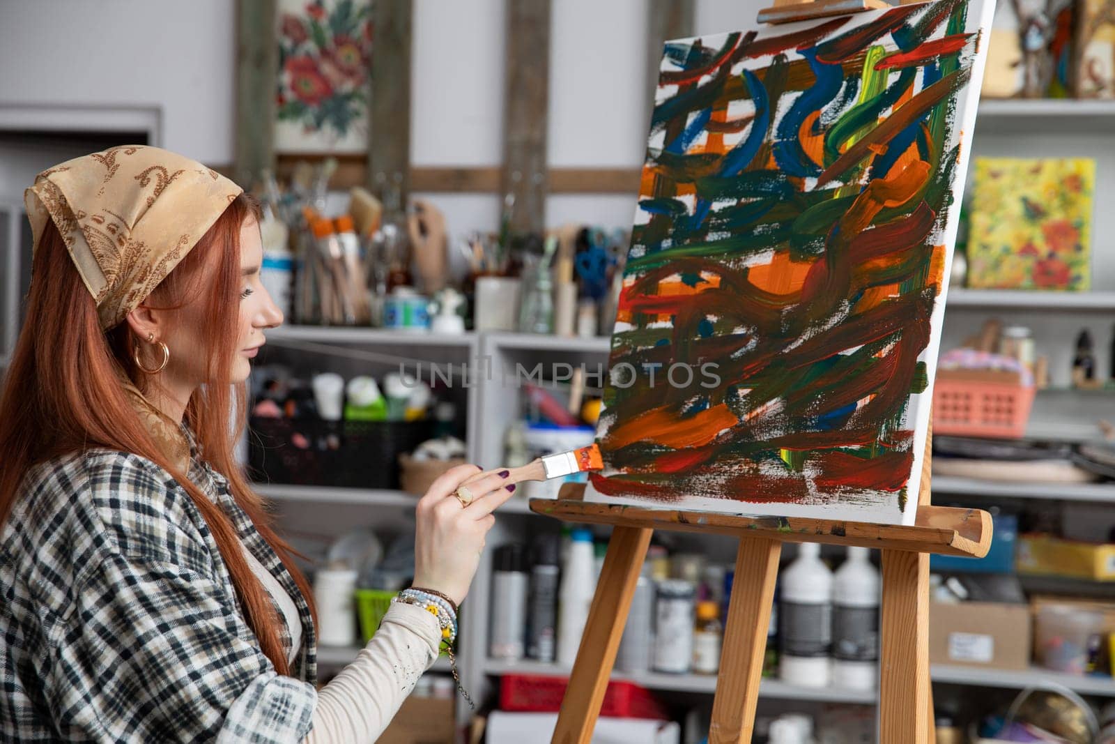 A talented woman artist passionately creates stunning abstract art within her vibrant and colorful studio space