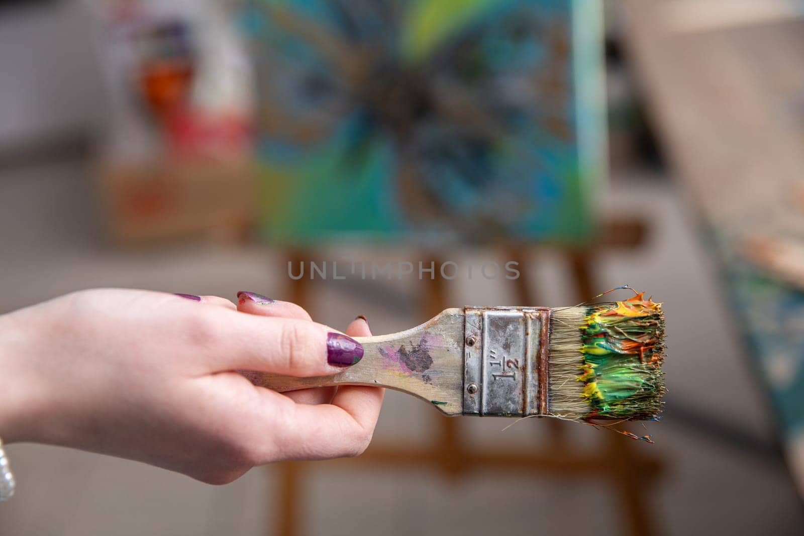A vibrant paintbrush is firmly held by an artist, showcasing immense creative potential in a bustling studio setting