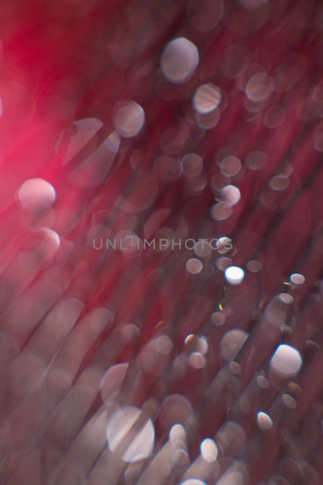 glare from water on a black mesh on a blurred red background. Abstract background.Close up. Defocused