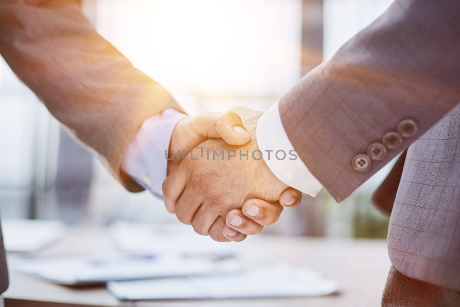 handshake in the office of two businessmen at the desk
