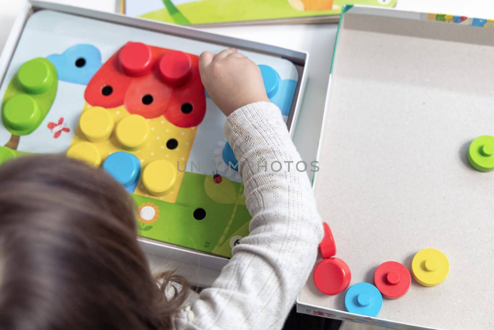 Two year old girl playing puzzle board game. High quality photo