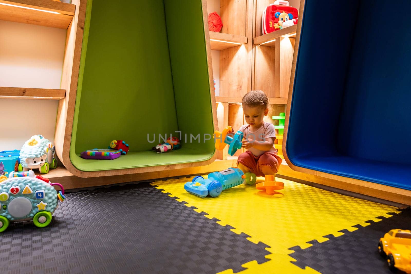 Toddler playing with toys in a colorful and modern playroom designed for learning and creativity
