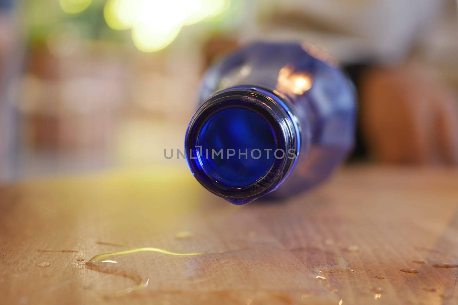 A blue water bottle tips over, creating a small puddle on the table.