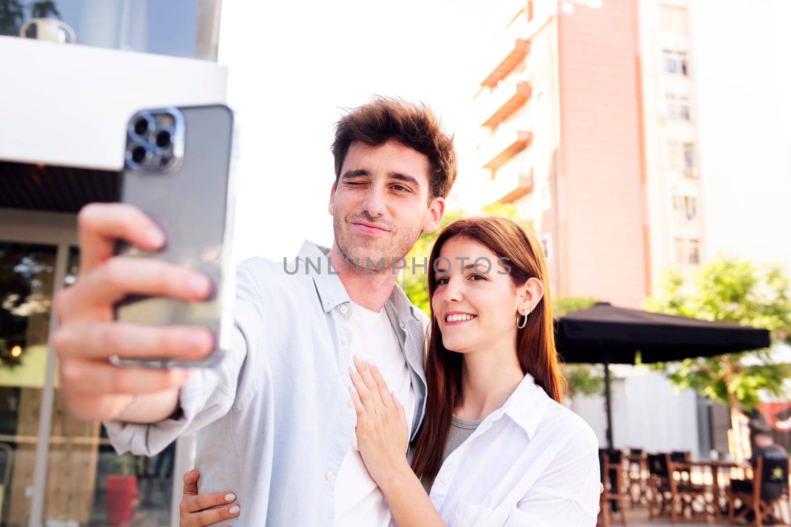 man and a woman are taking a selfie together, the man is holding a cell phone and the woman is smiling, concept of technology and urban lifestyle, copyspace for text