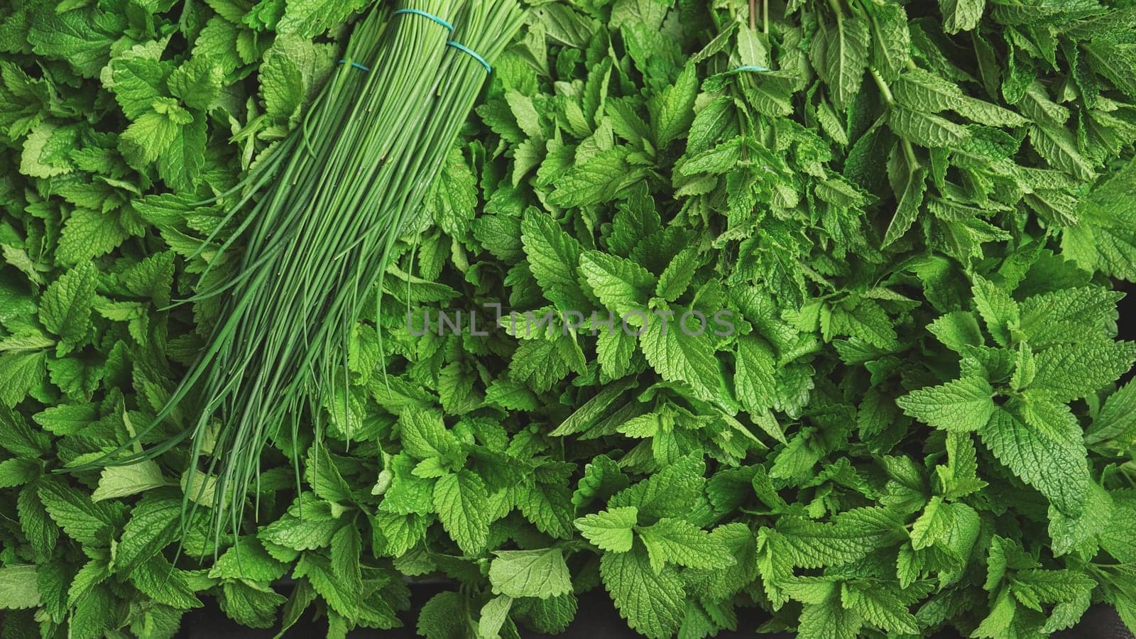Fresh mint leaves and bunch of chives on display at herbs market