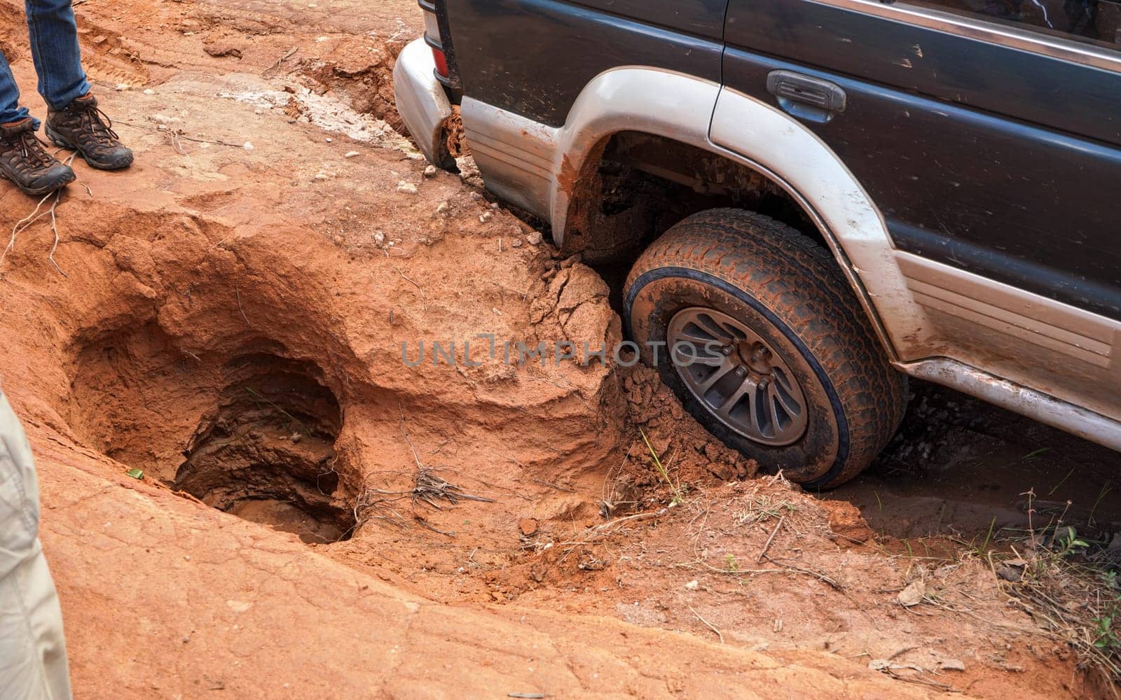 4wd vehicle driving over road with extreme holes and bumps, close up on rear wheel - roads are in very bad conditions in Andringitra, Madagascar, especially after rain