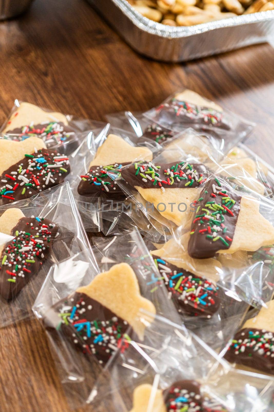 Carefully packaging Christmas cutout cookies, half-dipped in chocolate and presented in clear cellophane wrapping, perfect for festive gifting.