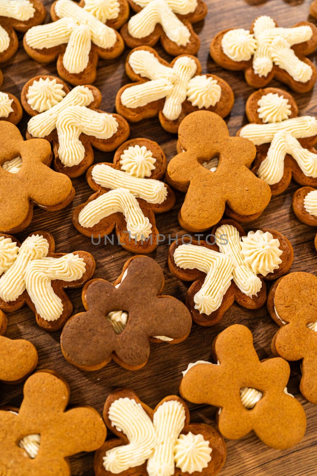 Making gingerbread man cookie sandwiches filled with eggnog buttercream, arrayed on a rustic wooden table, ideal for heartfelt Christmas gifting.