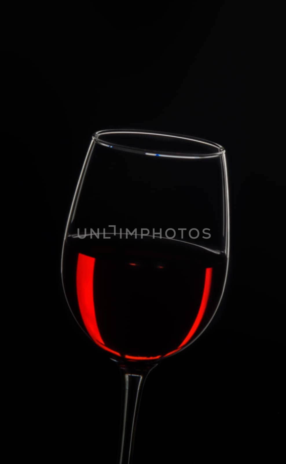 A sophisticated glass showcases deep red wine, reflecting light beautifully in contrast with a black backdrop.