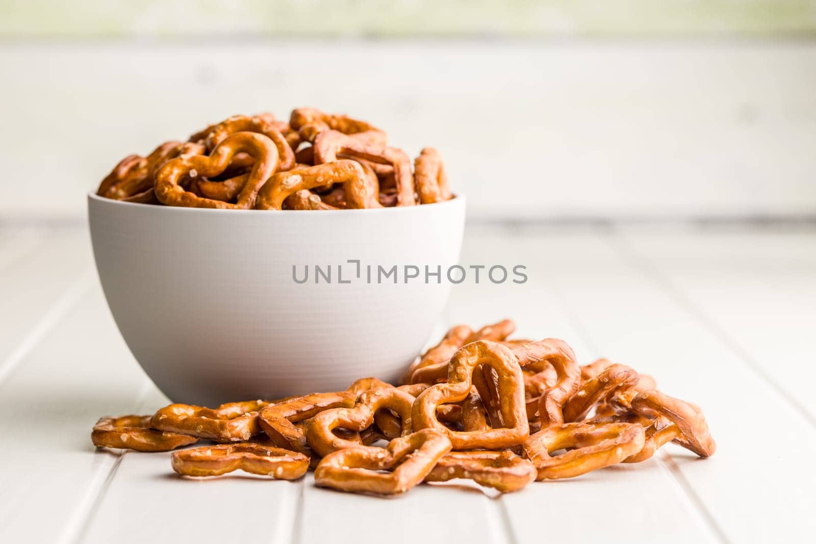 Heart shaped pretzel in bowl  on a white table.