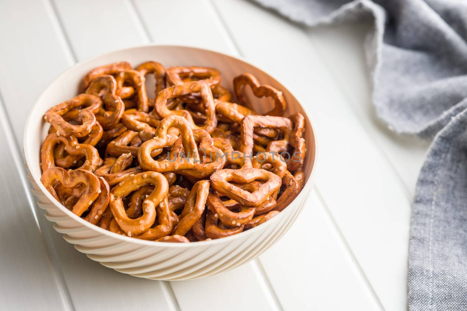 Heart shaped pretzel in bowl  on a white table.