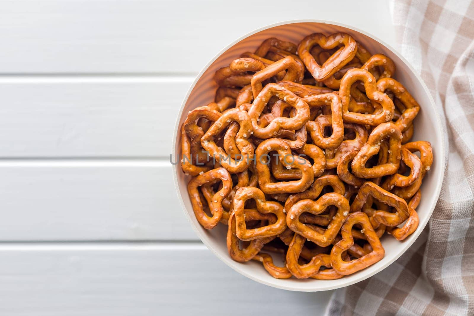 Heart shaped pretzel in bowl  on a white table. Top view.