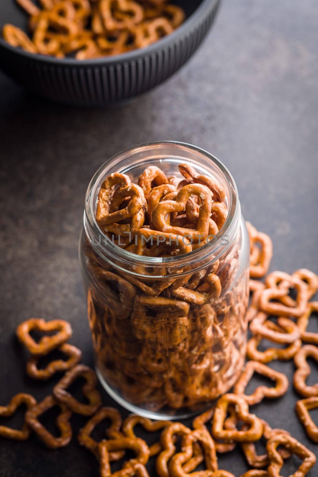 Heart shaped pretzel in jar on a black table.