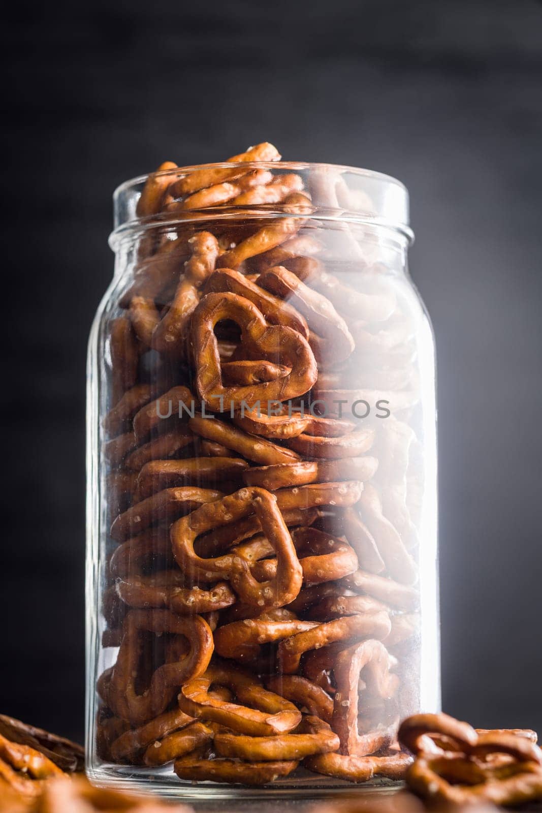 Heart shaped pretzel in jar on a black table.