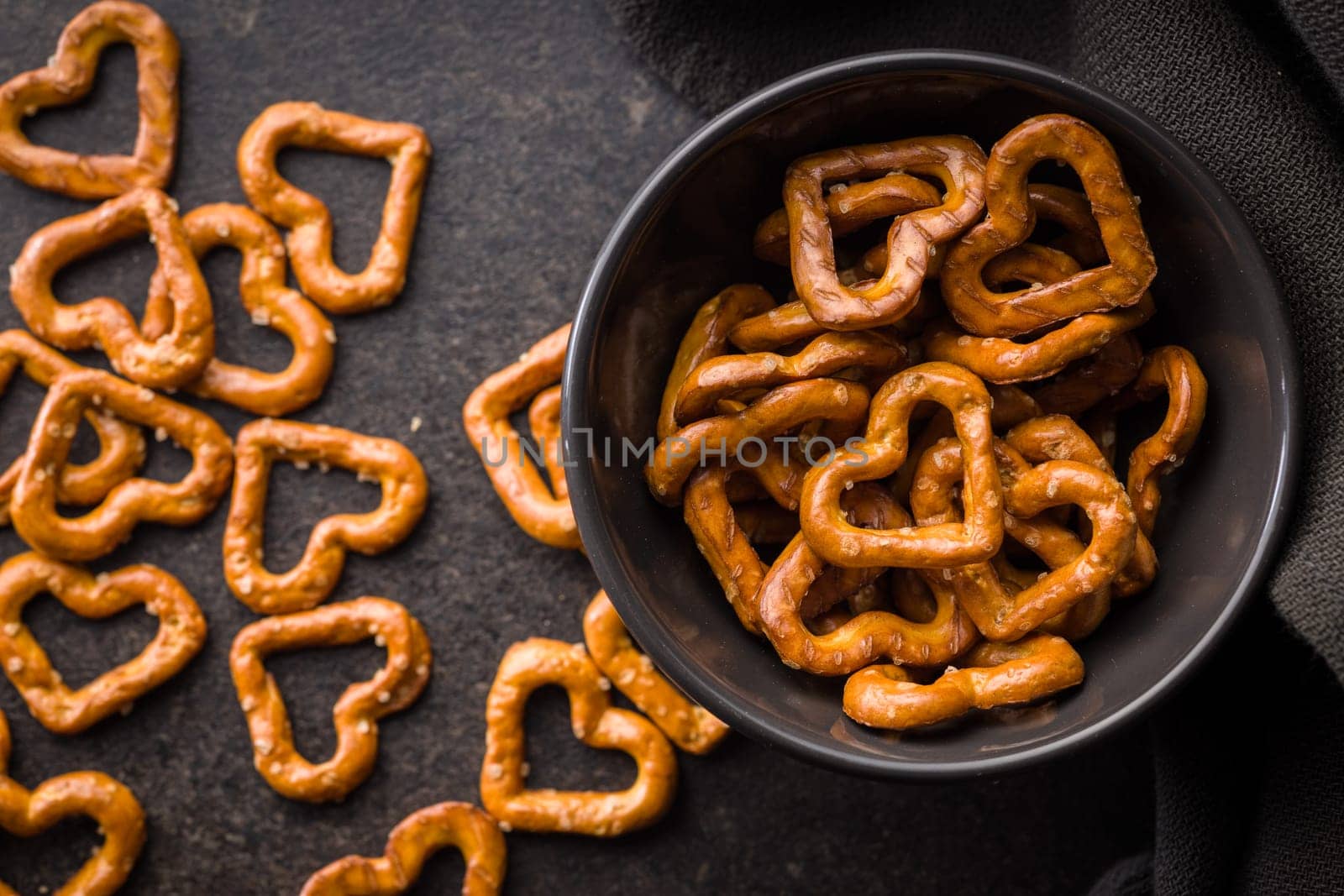 Heart shaped pretzel in bowl on a black table. Top view.