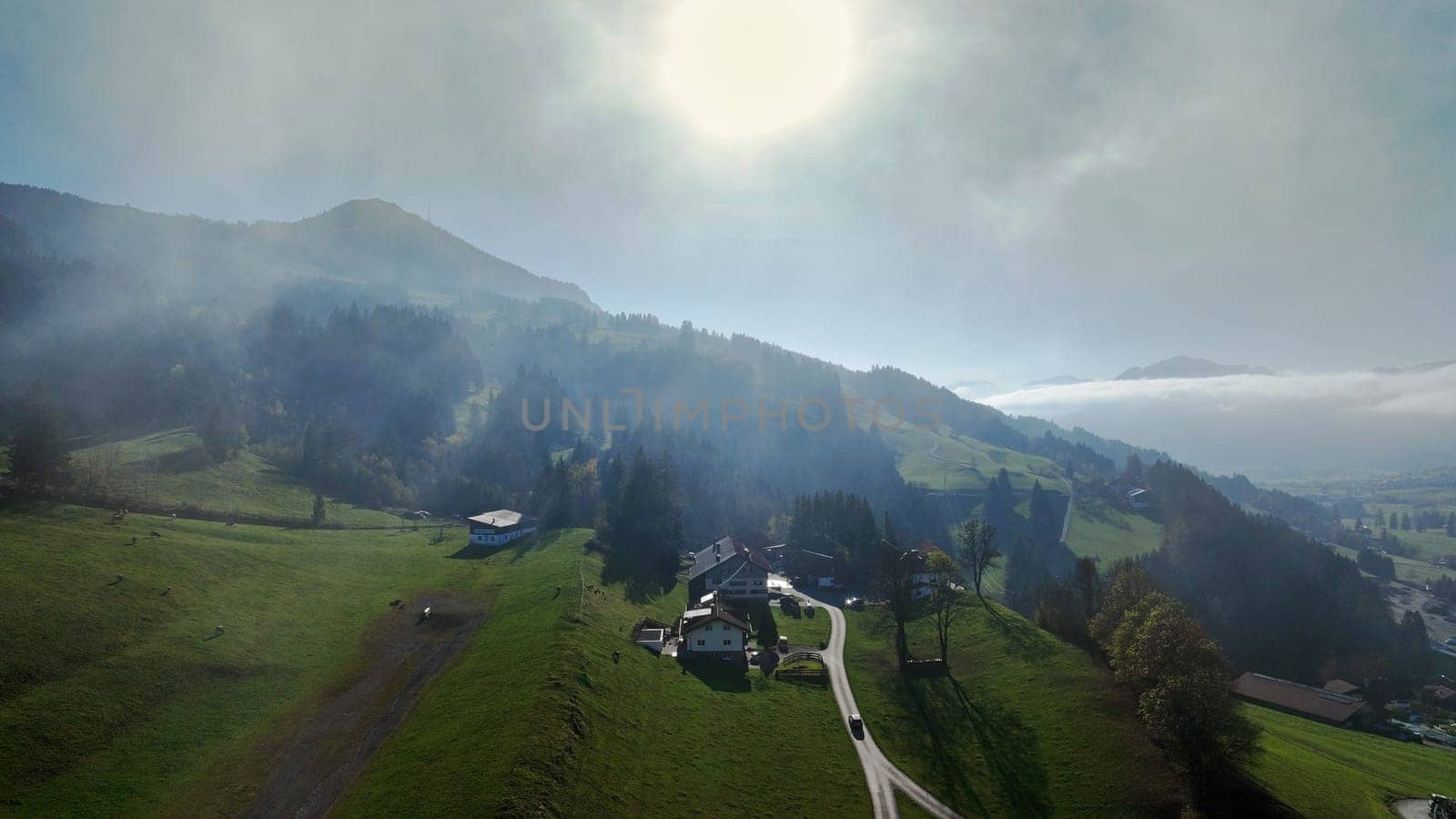 Drohnenfoto von einer Berglandschaft mit Straße mit Nebel im Gegenlicht der Sonne