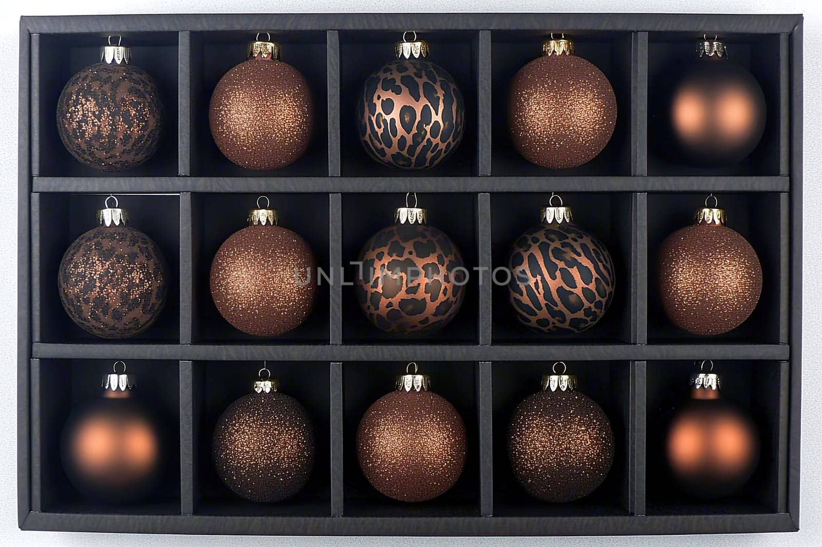 A beautifully organized display of bronze ornaments in various textures and patterns sits in a black storage box. This festive arrangement adds a touch of elegance to seasonal decor.
